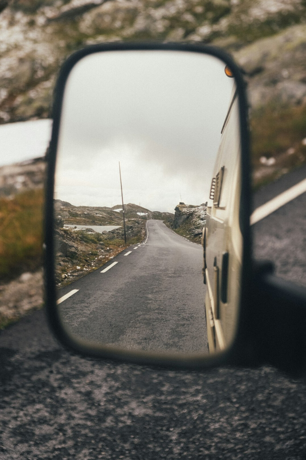 Rear view mirror inside a car with road behind